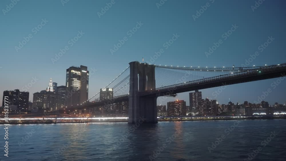 Majestic Brooklyn bridge and river at night in New York City. NYC skyline in the background. The view of the bridge in Lower Manhattan. Majestic Brooklyn bridge and river at night in New York City. NYC skyline in the background. The view of the bridge in Lower Manhattan.