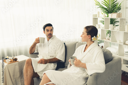 Beauty or body treatment spa salon vacation lifestyle concept with couple wearing bathrobe relaxing with drinks in luxurious hotel spa or resort room. Vacation and leisure relaxation. Quiescent