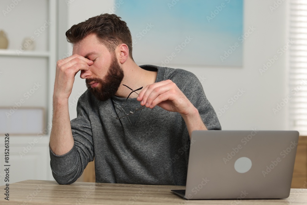 Overwhelmed man sitting with laptop at table indoors Overwhelmed man sitting with laptop at table indoors
