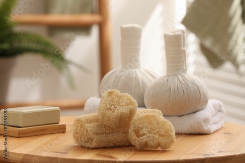 Loofah sponges, soap and herbal bags on wooden table indoors, closeup