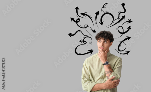 Portrait of pondering young man on grey background