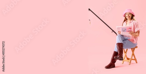 Happy young woman with fishing rod and newspaper on pink background with space for text photo