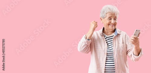 Happy senior woman using mobile phone on pink background with space for text