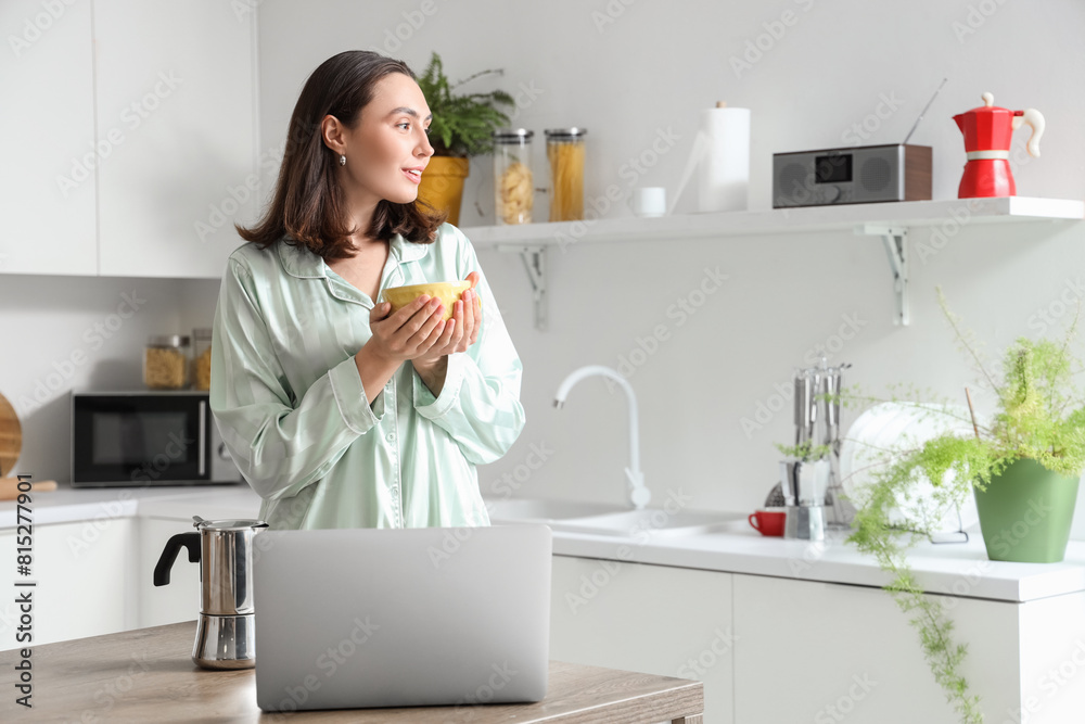 Pretty young woman with geyser coffee maker, cup of espresso and laptop in modern kitchen Pretty young woman with geyser coffee maker, cup of espresso and laptop in modern kitchen