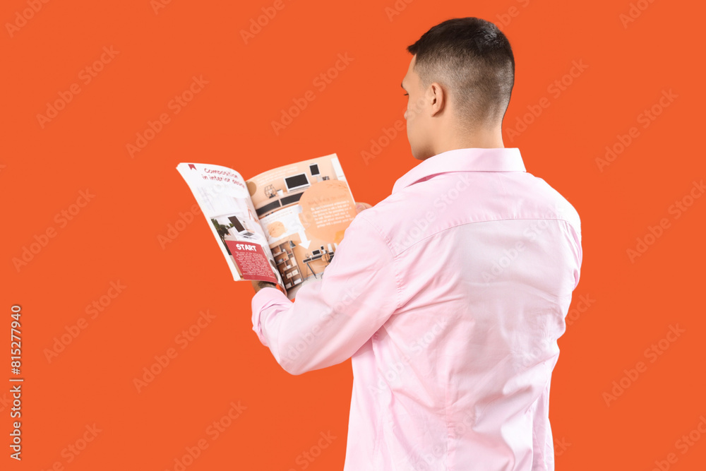 Young man reading magazine on orange background Young man reading magazine on orange background