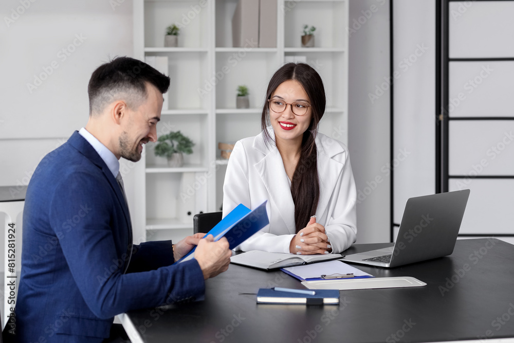 Human resources manager interviewing male applicant at table in office Human resources manager interviewing male applicant at table in office