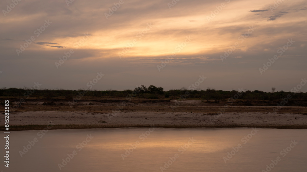 Long exposure shot of the river at nightfall. Panorama view of the river under a dramatic sunset sky. Beautiful sunlight and clouds reflection in the water surface.	
