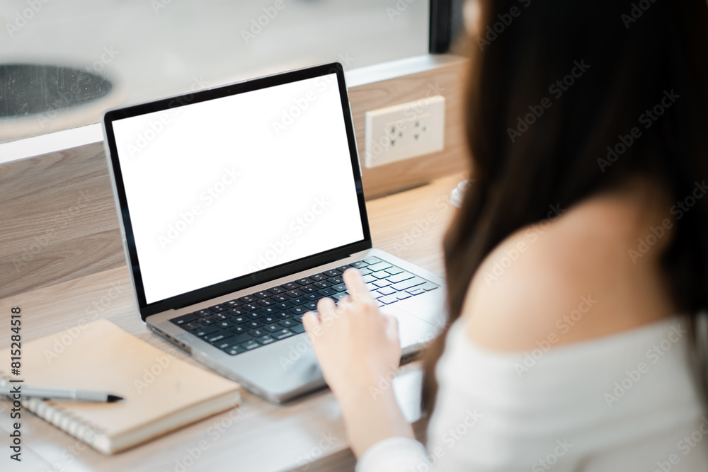 A woman is sitting at a desk with a laptop open and a notebook nearby. She is typing on the laptop, possibly working on a project or writing an email. Concept of productivity and focus A woman is sitting at a desk with a laptop open and a notebook nearby. She is typing on the laptop, possibly working on a project or writing an email. Concept of productivity and focus