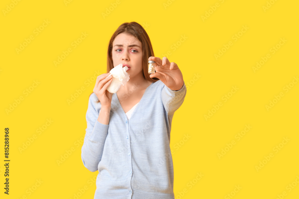 Young woman with tissue and jar of pills suffering from allergy on yellow background Young woman with tissue and jar of pills suffering from allergy on yellow background