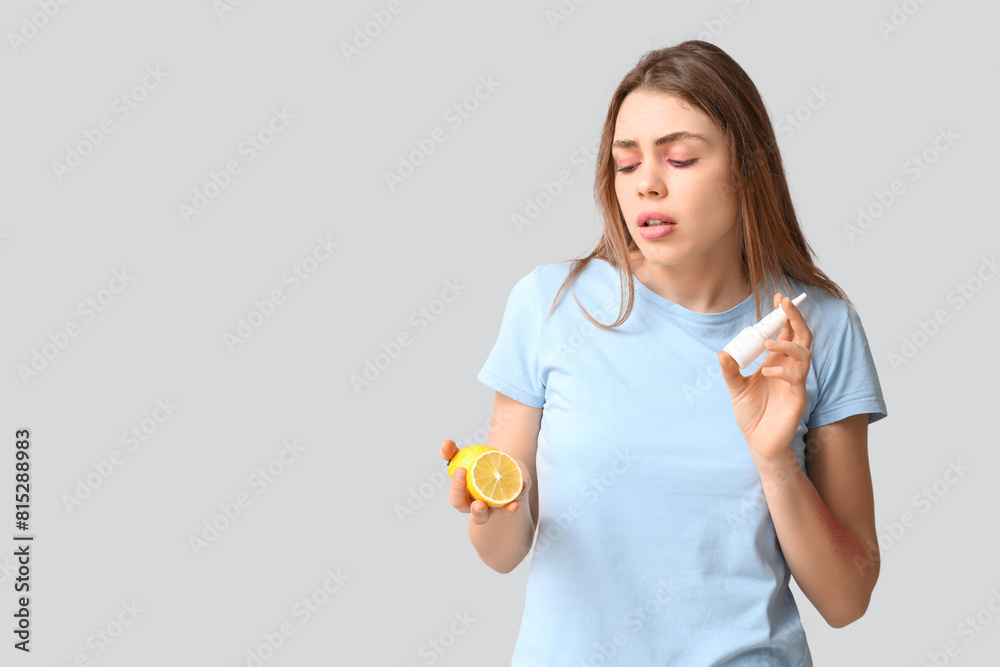 Young woman with lemon and nasal spray suffering from allergy on grey background Young woman with lemon and nasal spray suffering from allergy on grey background