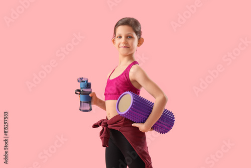 Little gymnast with water bottle and foam roller on pink background