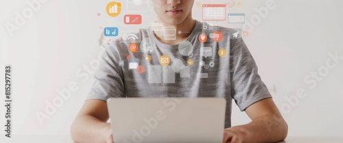 Close up of a young man typing on a laptop, against a white background with digital marketing icons and a search bar floating above his hand. photo