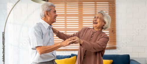 Asian active senior couple enjoy dance together in living room at home.