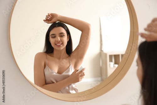 Young woman spraying deodor...