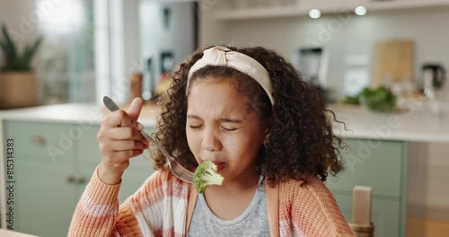 Young, girl and kitchen for tasting broccoli or food, dinner or lunch with healthy nutrition. Female child, vegetable and eating at table in home for wellness, diet with taste test or fork for meal photo
