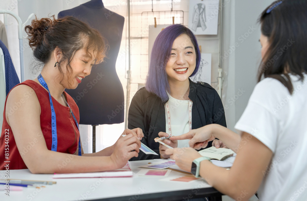 young female fashion designer with purple color hair and dressmaker discussing clothing design to woman customer with fashion sketch and color sample, concept of business,industry,design,dressmaking young female fashion designer with purple color hair and dressmaker discussing clothing design to woman customer with fashion sketch and color sample, concept of business,industry,design,dressmaking