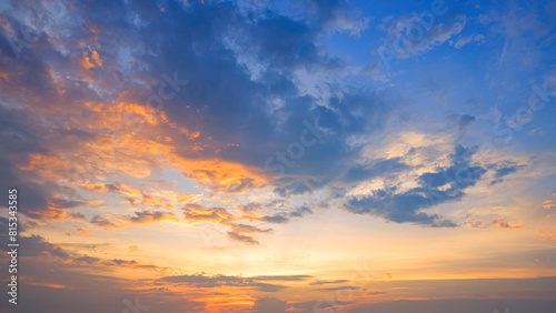 Dramatic sunset horizon sky with orange sunlight and dark clouds on blue idyllic dusk sky background in evening time