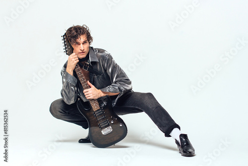 Tall attractive man holding electro guitar standing on the white background
