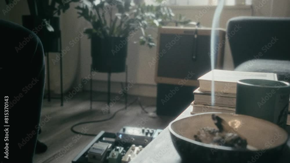 living room with sound equipment on the floor, potted plants, a sound box with a microphone on it, a couch, a table with some books and a incense living room with sound equipment on the floor, potted plants, a sound box with a microphone on it, a couch, a table with some books and a incense