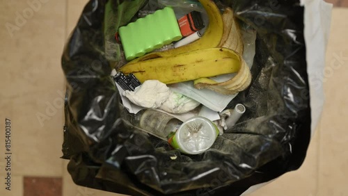 Used batteries are thrown into a bin with food and household waste. Close up
