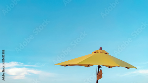 Yellow parasol against bright blue sky background. Summer vacation. Beach umbrella. © Win Nondakowit