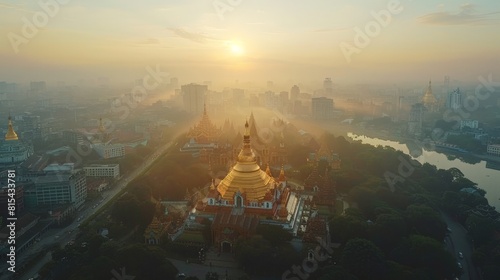 Aerial view of the Shwedagon Pagoda in Yangon, Myanmar, with its golden stupa shining brightly amid the bustling city and lush green parks. 