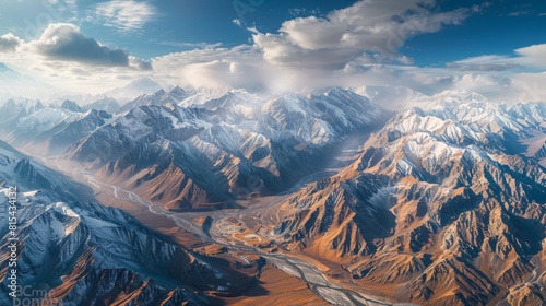 Aerial view of the Pamir Mountains in Tajikistan  showcasing the rugged peaks  deep valleys  and remote villages amidst dramatic landscapes.     