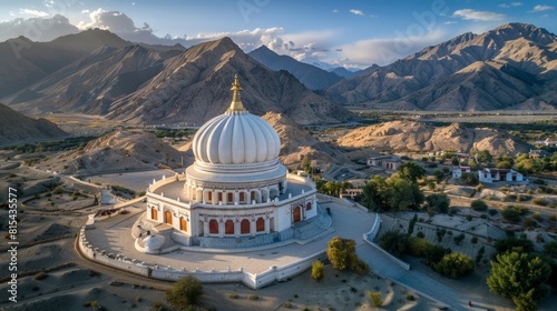 Aerial view of the Shanti Stupa in Leh, India, with its white dome structure set against the backdrop of the Himalayan mountains and the surrounding desert landscape. 