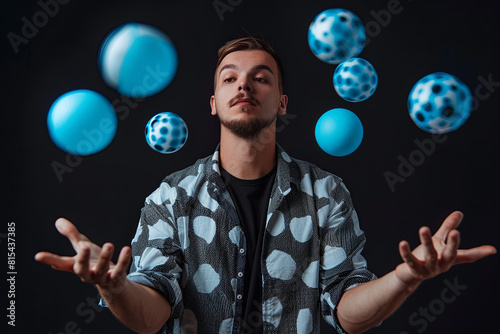 Man juggling blue balls on black background. Stylish Man with black and white shirt posing for the camera
 photo