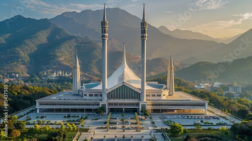 Aerial view of the Faisal Mosque in Islamabad, Pakistan, featuring its modern design with white minarets and tent-like structure set against the Margalla Hills.      photo