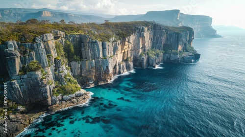 Aerial view of the Tasman Peninsula in Tasmania, Australia, showcasing the dramatic sea cliffs, clear blue waters, and lush green forests.      photo