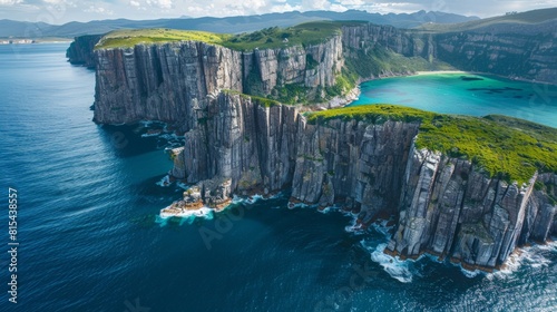 Aerial view of the Tasman Peninsula in Tasmania, Australia, showcasing the dramatic sea cliffs, clear blue waters, and lush green forests.      photo