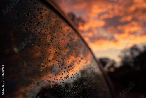 Water droplets on a car window reflecting a colorful sunset