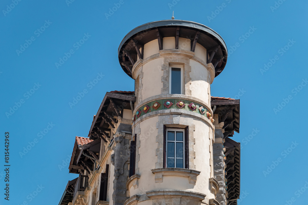 Detalhes de uma casa antiga com a fachada frontal arredondada em forma de torre em meio a um céu azul