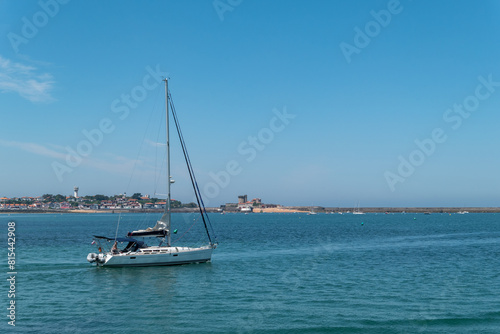 Um barco a navegar no mar com parte da cidade e do porto de Ciboure ao fundo no País Basco francês