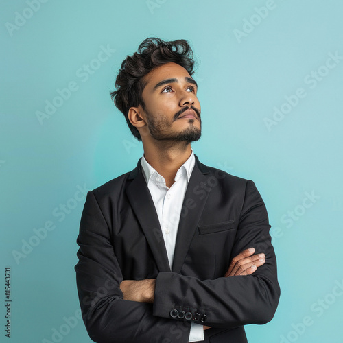 young handsome indian businessman with arms crossed looking up