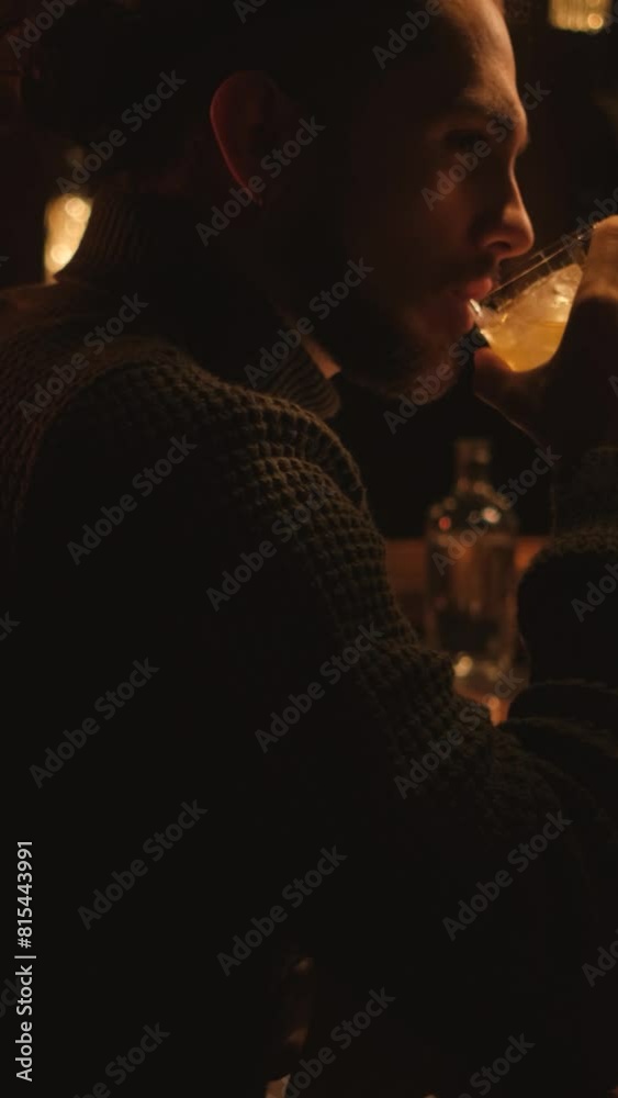 Portrait of a young guy in a night bar. A man drinks a cocktail and rests. Vertical video. Portrait of a young guy in a night bar. A man drinks a cocktail and rests. Vertical video.