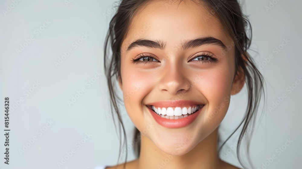 A close-up of a woman smiling as she holds a toothbrush, with one in her mouth A close-up of a woman smiling as she holds a toothbrush, with one in her mouth