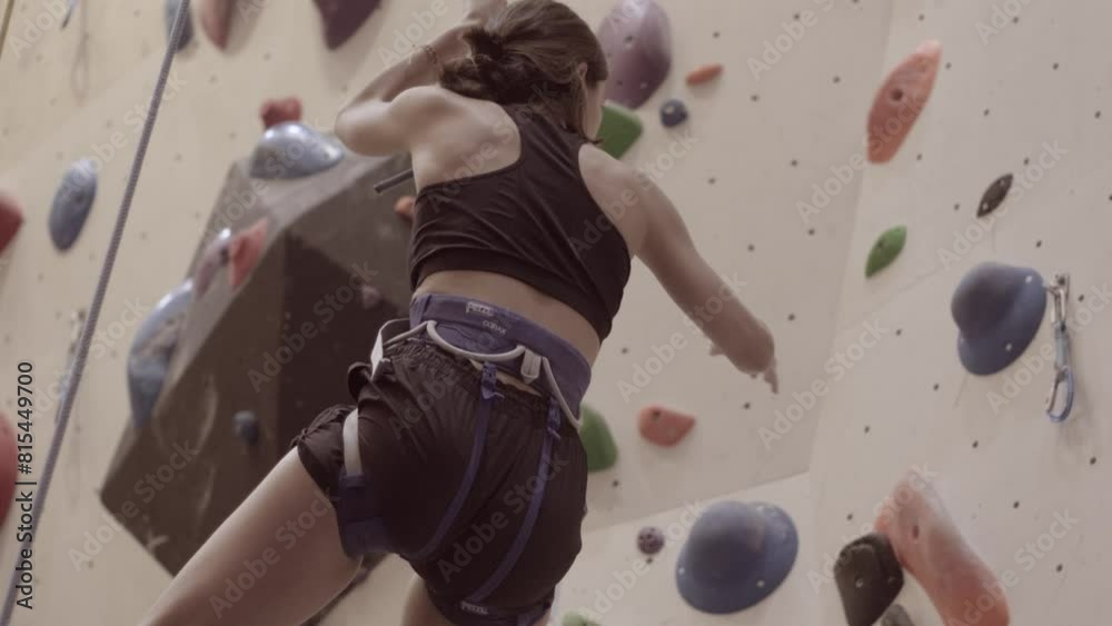 Woman Climbing and reaching the top of a outdoor bouldering wall with a rope Woman Climbing and reaching the top of a outdoor bouldering wall with a rope