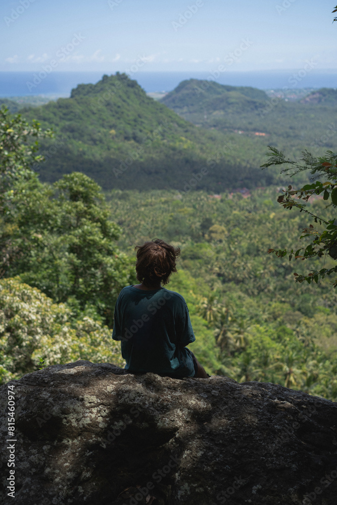 Man looks at the valley from the top of the mountain.