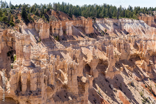 A rocky cliff full of hodoos with a few trees in the background photo