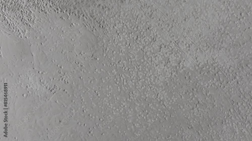 Aerial upward and orbit movement of footsteps on the sand of the Great Salt Lake, Utah on a sunny day.
