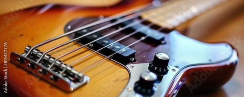 Close-up image of an electric bass guitar with focus on the strings, pickups, and volume knob on a wooden textured background.
