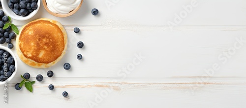 Top view of a copy space image featuring light background with cottage cheese pancakes sour cream and blueberries Suitable for breakfast or lunch