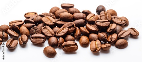A high quality macro image of roasted brown and black coffee beans is isolated on a white background providing ample copy space for text