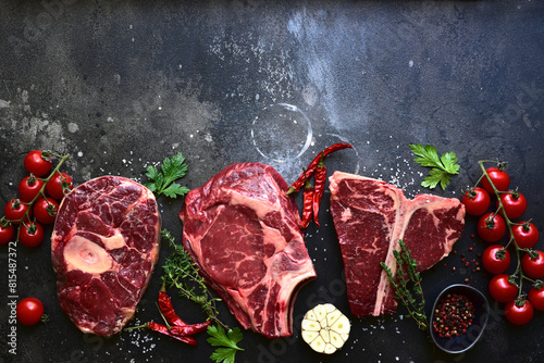 Raw organic marbled beef steaks : ossobuko, rib eye ( cowboy ) , T - bone. Top view with copy space. photo