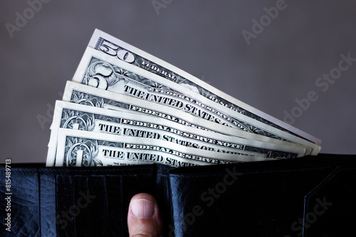 Close-up of US dollar banknotes half way out of a black wallet photo