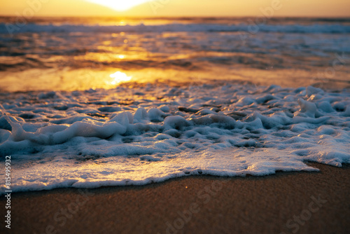 Foamy waves wash along the shore on sunrise