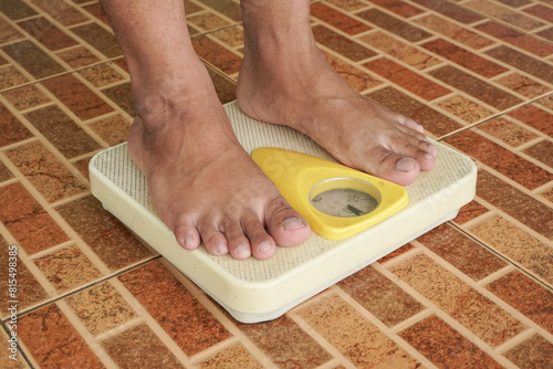 Close up of man legs standing on weight scales. Standing on floor scale at home. A man checking his weight
