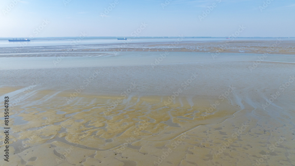 Aerial view of sea in low tide with tankers in the background